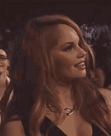 a woman in a black dress is sitting in a crowd of people .