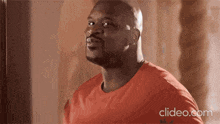 a bald man in a red shirt is looking up at the sky .