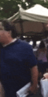 a blurry picture of a man in a blue shirt standing in front of a tent
