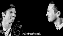 two men are talking to each other in a black and white photo and they are bestfriends .