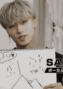 a young man is holding a piece of paper that says sa on it