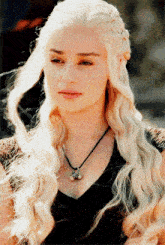 a woman with blonde hair is wearing a necklace with a pendant