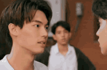 a group of young men are standing next to each other looking at each other .
