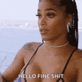 a woman in a bikini is standing in front of a body of water and says `` hello fine shit '' .