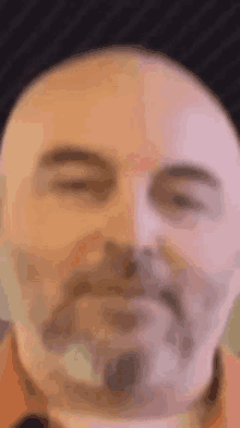 a bald man with a beard is looking at the camera with his eyes closed .