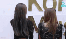two women are standing in front of a sign that says kof