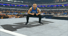 a wrestler squatting down in a wrestling ring with the word raw on his shirt
