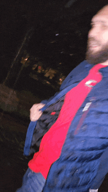 a man with a beard is wearing a blue jacket and a red shirt
