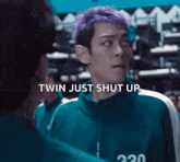 a man with purple hair is talking to another man while wearing a green jacket .