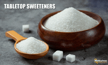 a wooden bowl of tabletop sweeteners next to a wooden spoon and sugar cubes