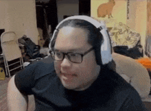 a man wearing headphones and glasses is sitting at a desk in a room .