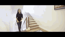 a woman walking down a set of stairs with a picture on the wall behind her