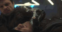 a man in a black suit is holding a person 's leg in a dark room .