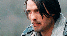 a man with a cigarette in his mouth wearing a denim jacket