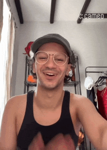 a man wearing glasses and a baseball cap is smiling in front of a cameo sign