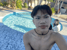 a shirtless man taking a selfie in front of a pool
