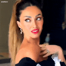 a woman with a ponytail and red lipstick is wearing a black top and earrings .