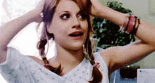 a woman in a hospital gown is holding her hair in pigtails and making a funny face .