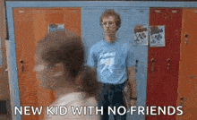 a man in a blue shirt is standing in front of a row of lockers in a school .