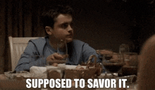 a young boy is sitting at a table with a glass of wine and a basket of food .