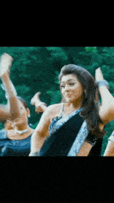 a woman in a black and silver saree is dancing in front of a crowd .