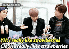 a group of young men are sitting next to each other on a couch eating strawberries .
