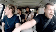 a group of people are sitting in the back seat of a car and laughing .