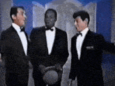 three men in tuxedos are standing next to each other in a room .