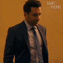 a man in a suit and tie is covering his face with his hands and the words saint-pierre are behind him