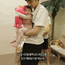 a man is holding a baby in his arms with korean writing on the bottom right