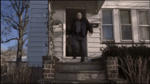 a man is walking out of a house with a mailbox on the porch