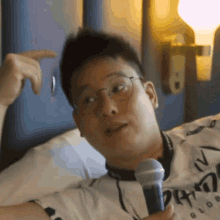 a man with glasses is holding a microphone and pointing