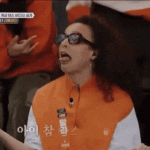 a woman wearing sunglasses and an orange shirt is making a funny face