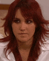 a close up of a woman 's face with red hair and a white shirt