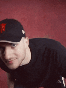 a man wearing a black shirt and a black hat with the letter p on it