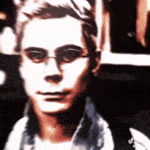 a man wearing glasses and a scarf looks at the camera .