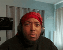 a man wearing headphones and a red head scarf looks surprised
