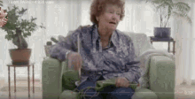 a video of an elderly woman sitting on a couch playing a game