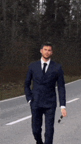 a man in a white tuxedo and black bow tie is walking down the street .