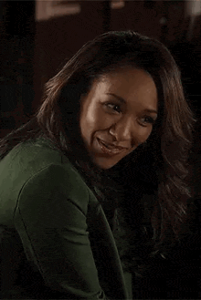 a close up of a woman wearing a green sweater and smiling .