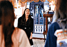 a woman in a black dress is standing in a room with other people .