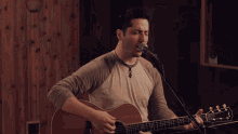 a man playing an acoustic guitar with a microphone attached to it