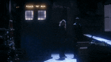 a man and a woman are standing in front of a police box