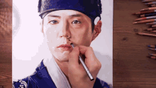 a drawing of a man 's face with colored pencils on a table