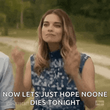 a woman is standing in a field with her hands in the air and says `` now lets just hope no one dies tonight '' .