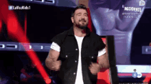 a man in a black vest is dancing on a stage in front of a screen that says lavozkids1