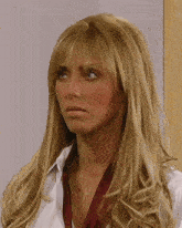 a woman with long blonde hair and bangs is wearing a white shirt