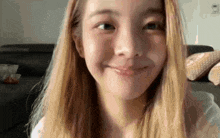 a close up of a woman 's face with long blonde hair smiling .