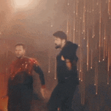 two men are dancing in front of a wall that is covered in sparkles .