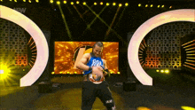 a wrestler wearing a blue shirt that says ' raw ' on it is on a stage